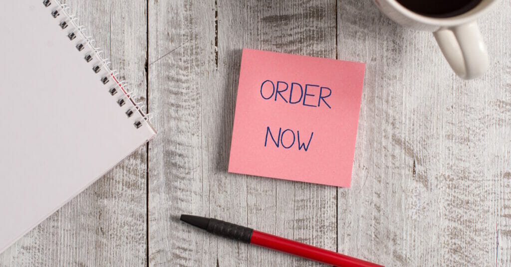 Handwriting text Order Now. Concept meaning the activity of asking for goods or services from a company Stationary placed next to a cup of black coffee above the wooden table.